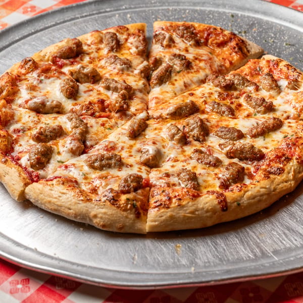 Sausage pizza, sliced into eight pieces, on a metal pan with a red and white checkered tablecloth.